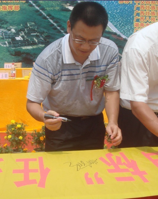 廣西新港灣公司副總經(jīng)理姚方明在“奮戰100天，如期實(shí)現魚(yú)梁工程截流、通航、發(fā)電‘三大目標’”橫幅上簽字